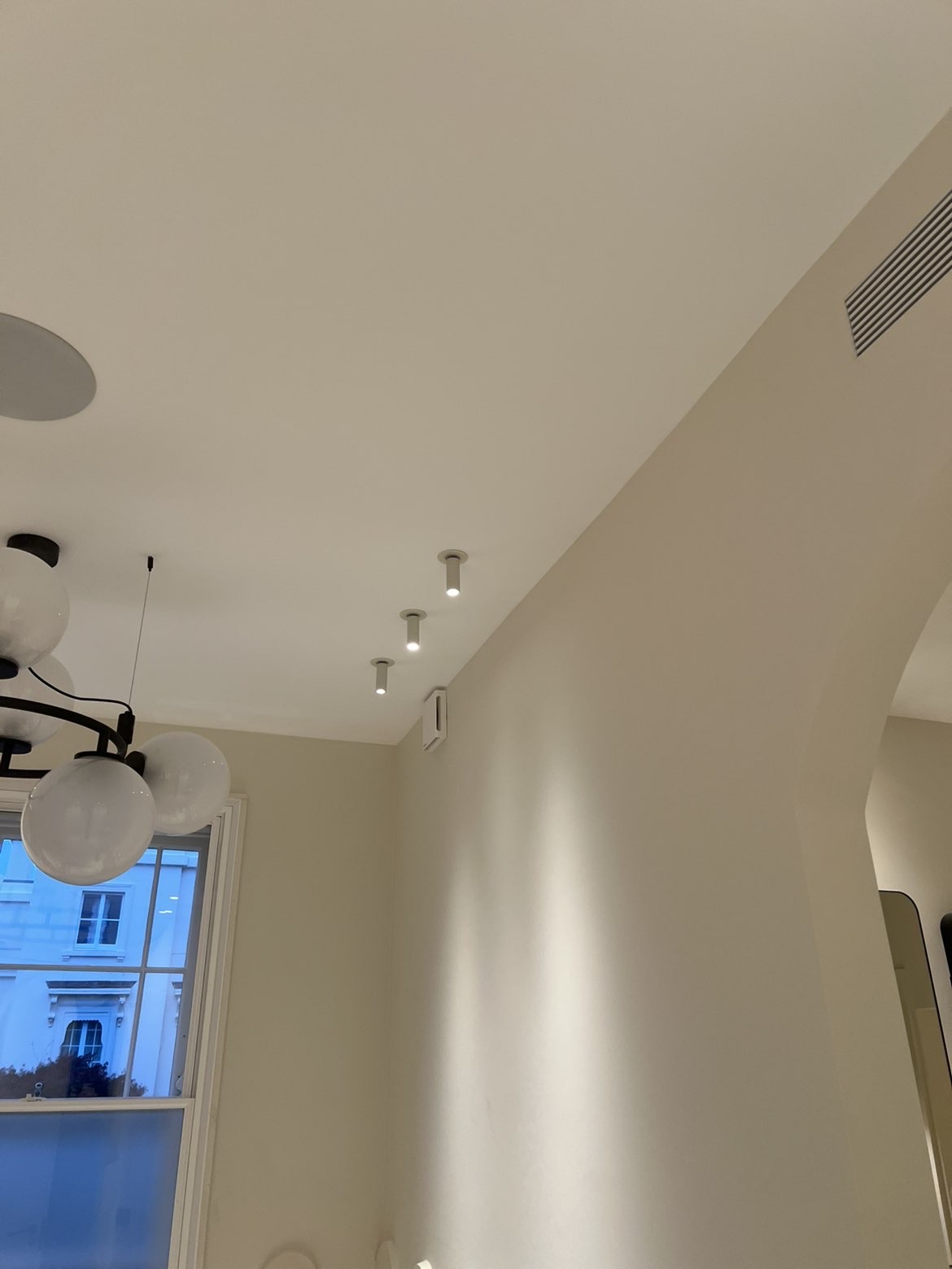 Row of surface-mounted adjustable spotlights washing a wall with light