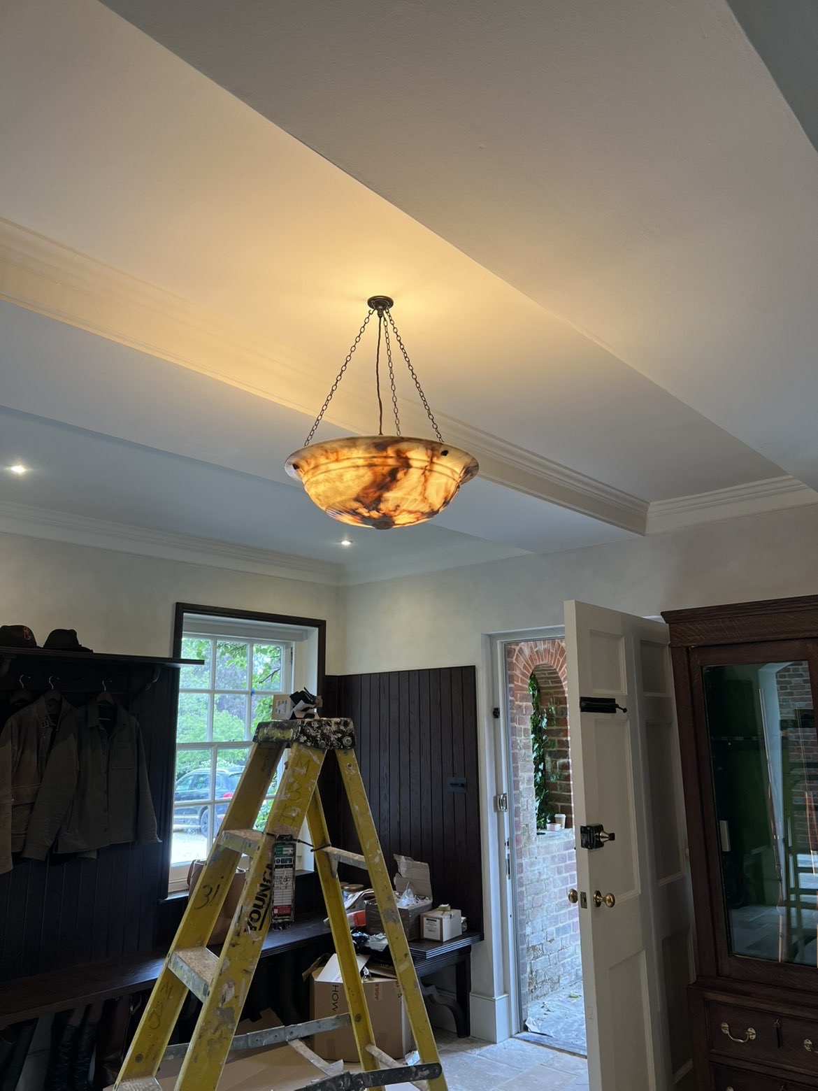 Alabaster bowl pendant light lit on a chain, with recessed downlights around it