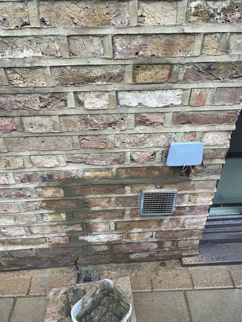 External brick wall with a service enclosure and vent during installation works
