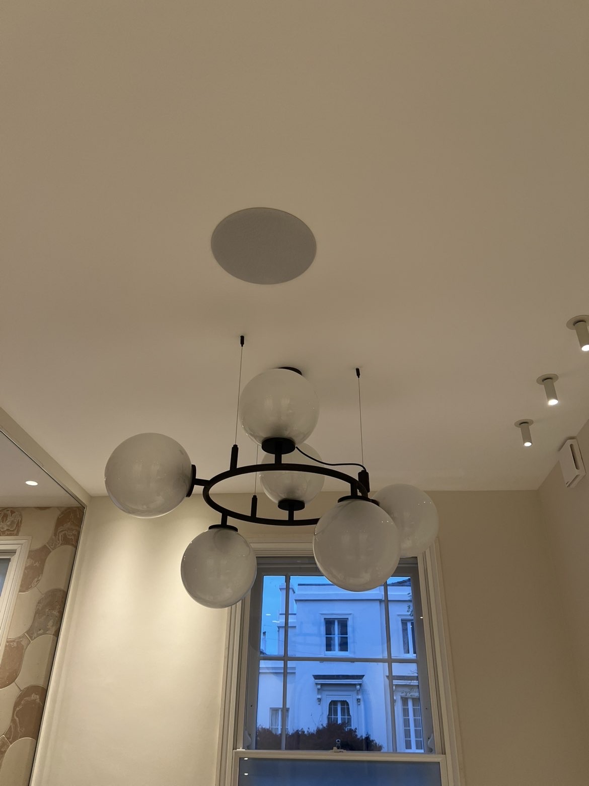 Glass globe pendant light fitting hanging beside a window, with downlights