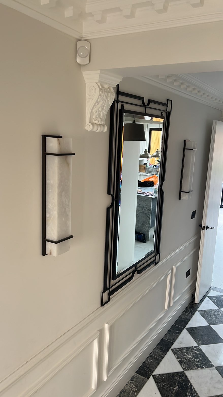Slim alabaster and bronze wall lights fitted in a panelled hallway