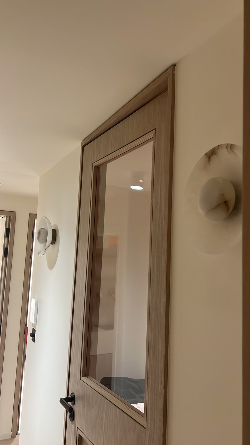 Round alabaster wall lights fitted either side of a landing doorway