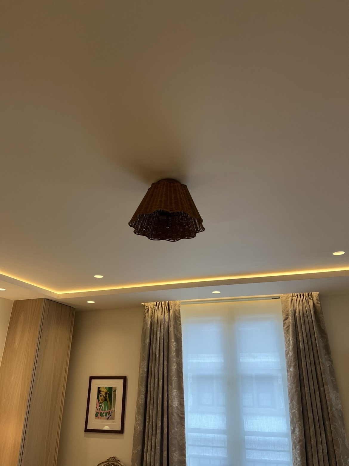 Bedroom ceiling with concealed cove LED strip lighting, downlights and a wicker pendant